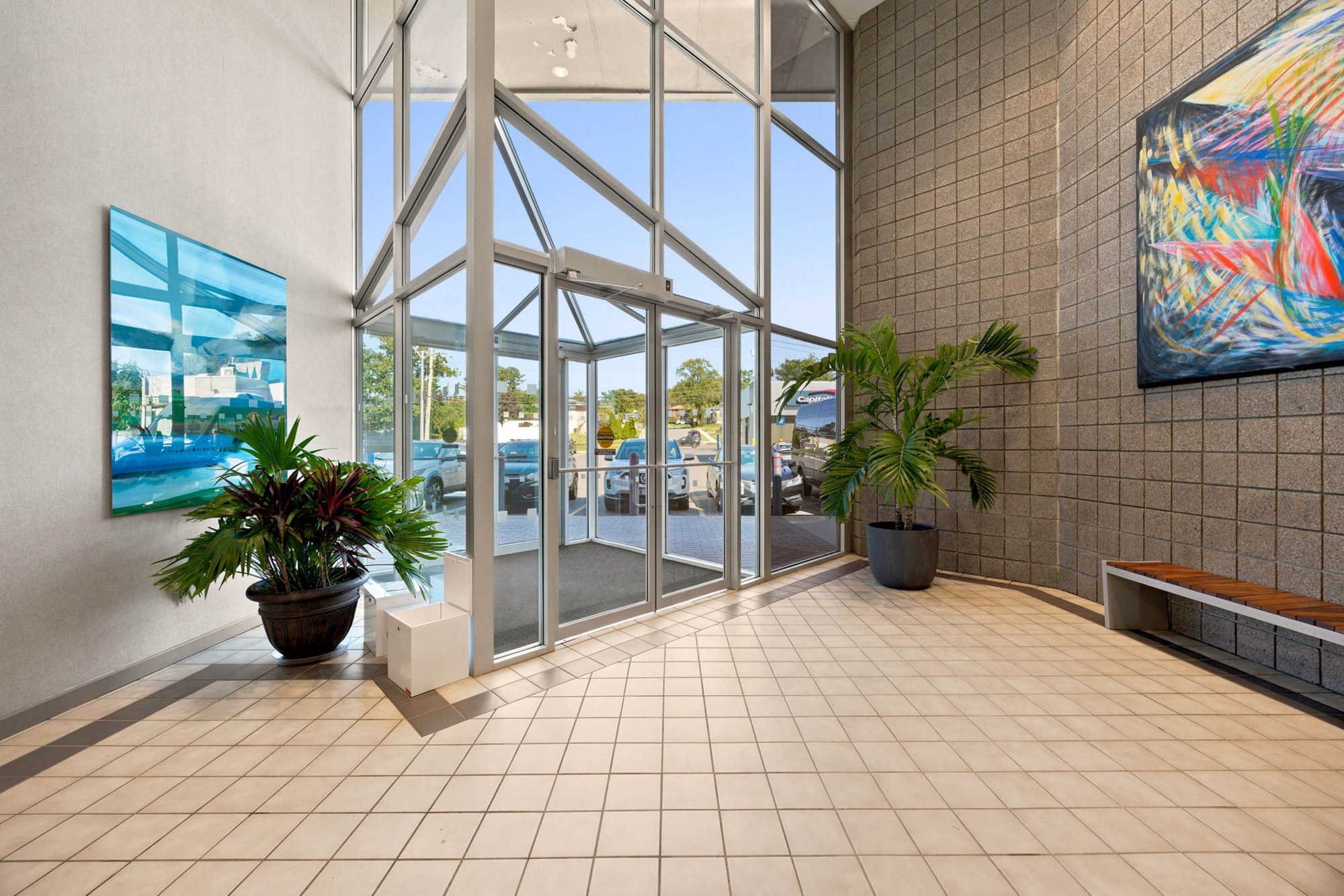 Double-height glass lobby with artwork and greenery
